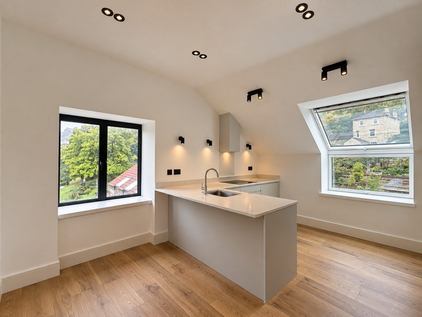 Unit 10 kitchen: a peninsula beneath the sloping ceiling, with a dormer window looking out to stone houses on the hillside.